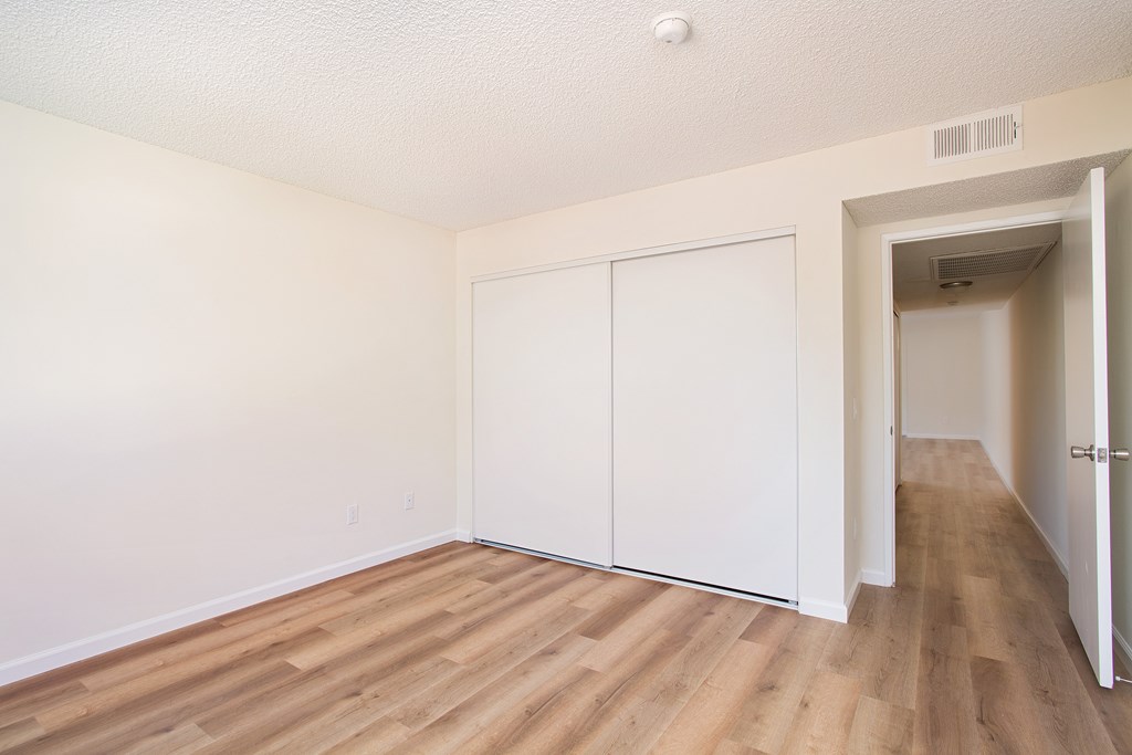 A room with white walls and wooden flooring with a white door.