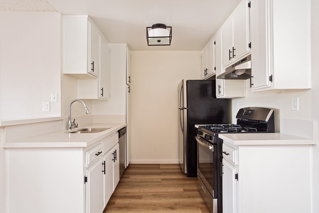 A kitchen with white cabinets and black appliances.