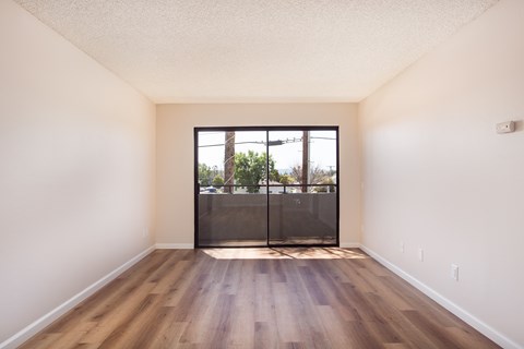 A room with a sliding door leading to a balcony.
