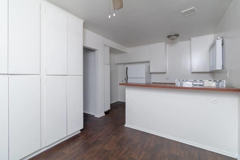 an empty kitchen with white cabinets and a counter top