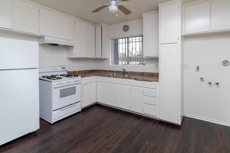 an empty kitchen with white appliances and white cabinets