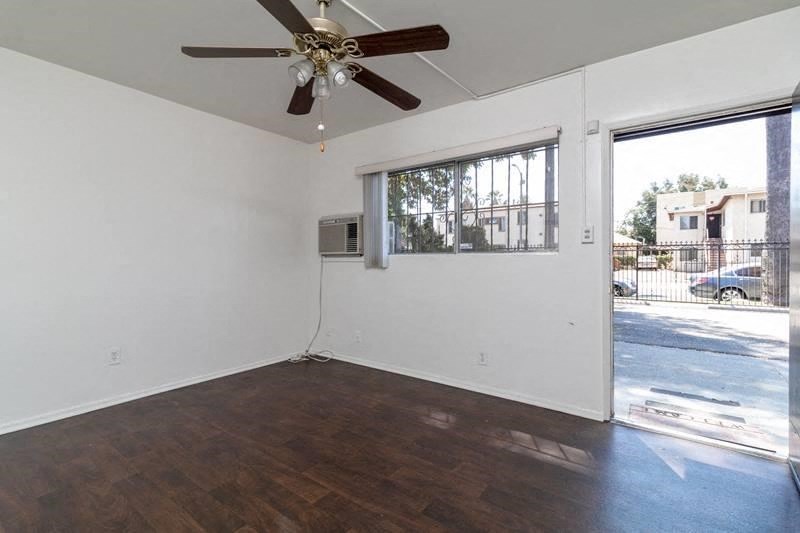 an empty living room with a ceiling fan and a window