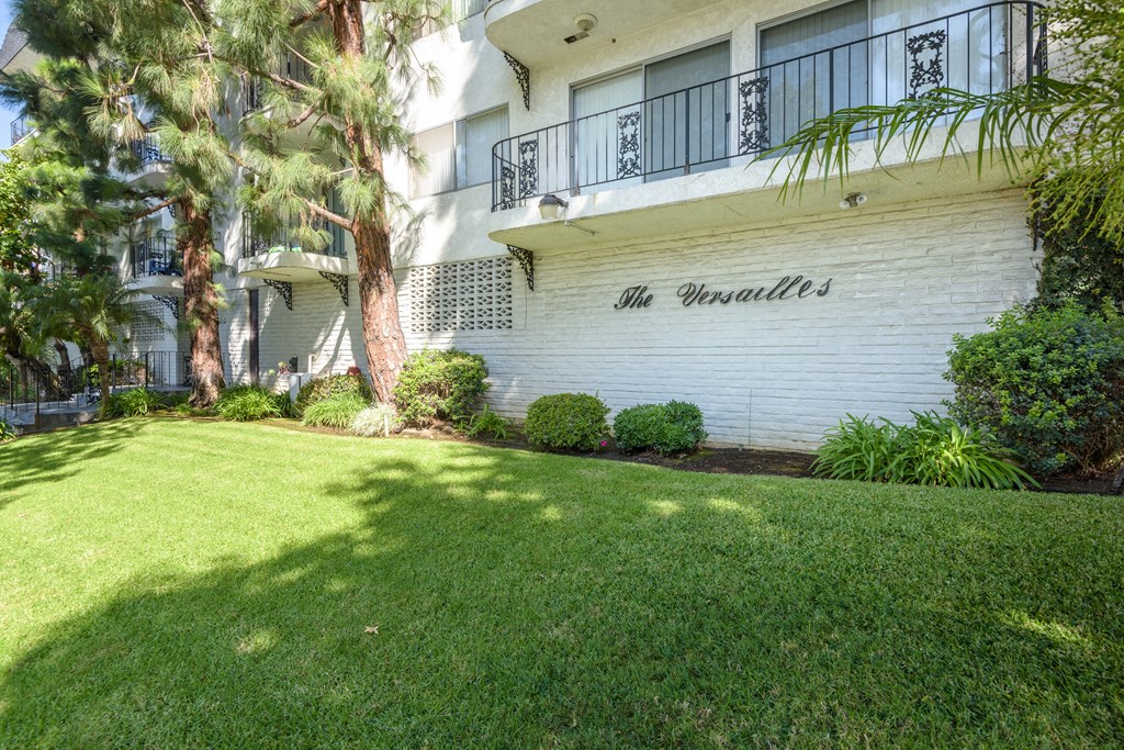 an image of the front of an apartment building with green grass and trees