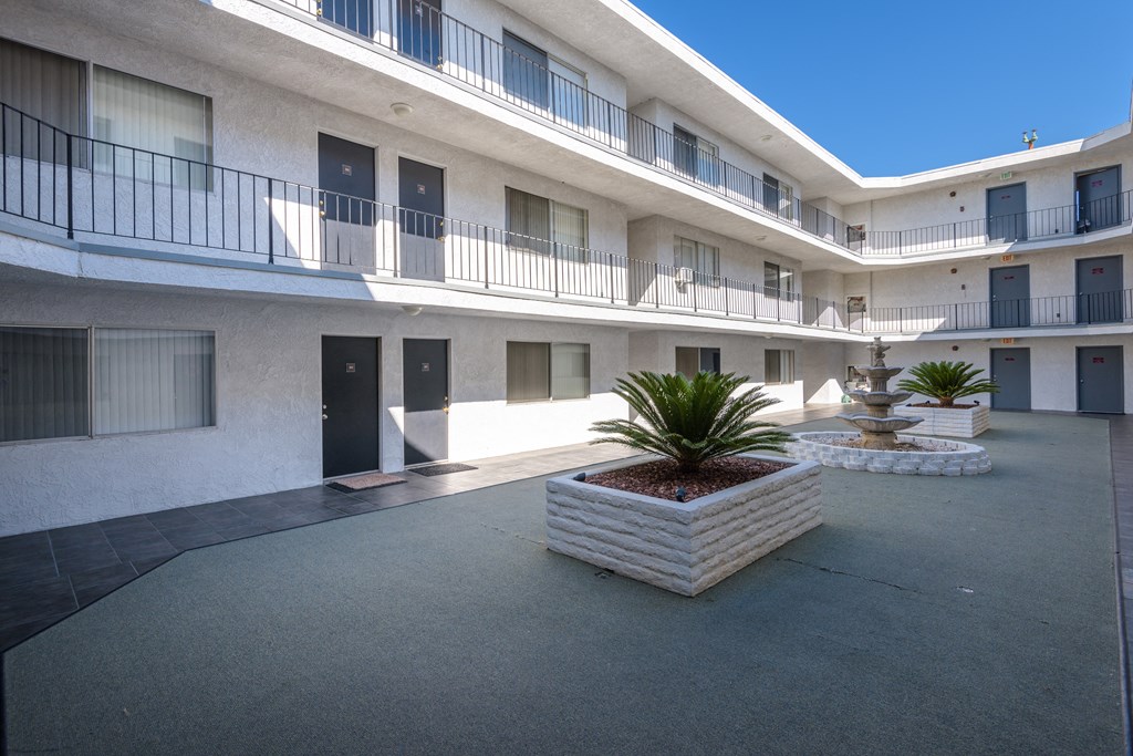 a courtyard with a fountain and a white building with black doors