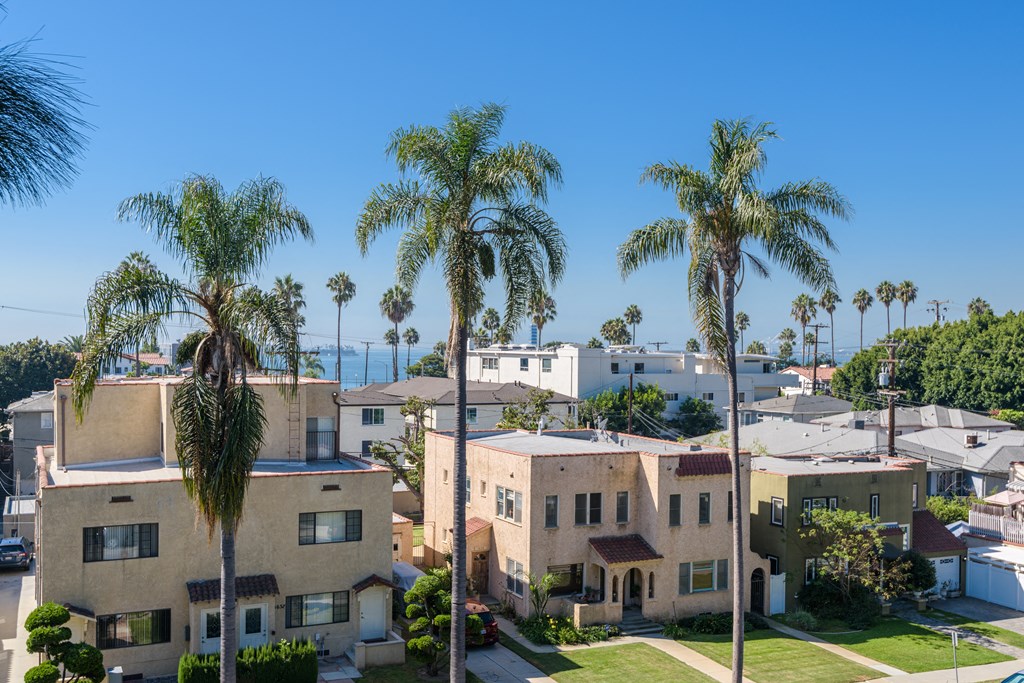 an aerial view of a neighborhood with palm trees and the ocean in the background