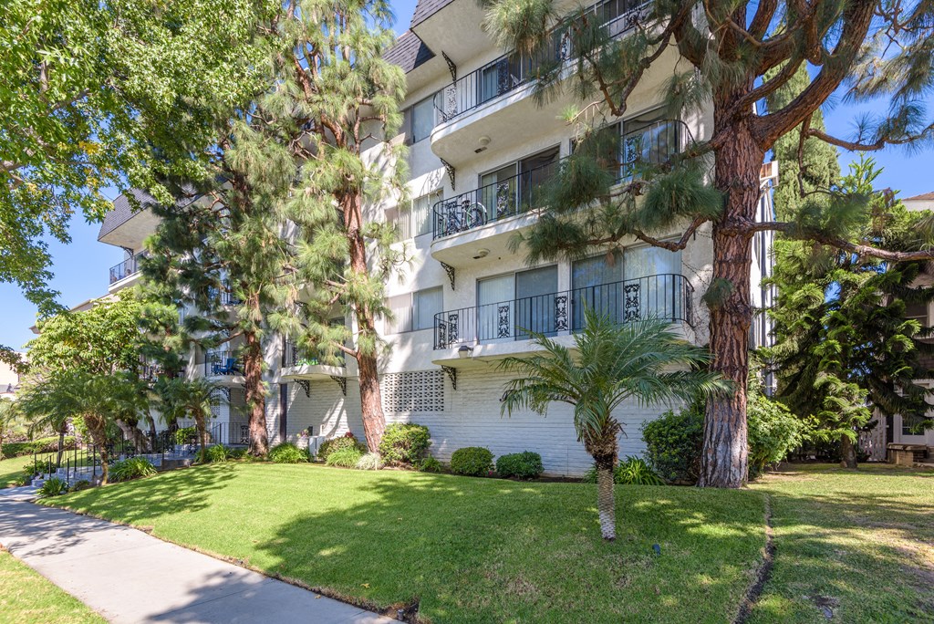 an apartment building with a lawn and trees in front of it