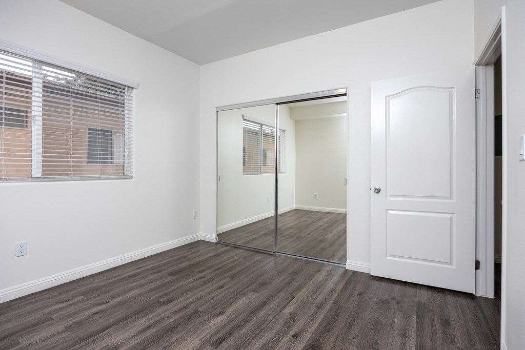 a bedroom with hardwood floors and white walls