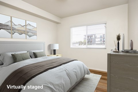 A bedroom with a large bed and a window with blinds.