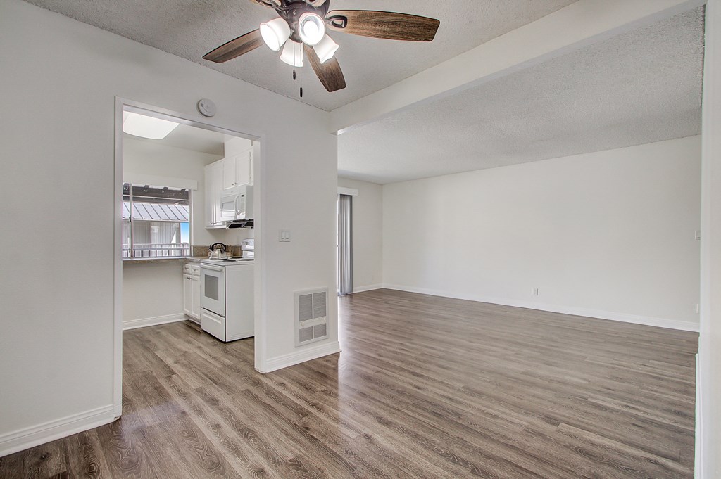 a bedroom with a ceiling fan and a kitchen in the background