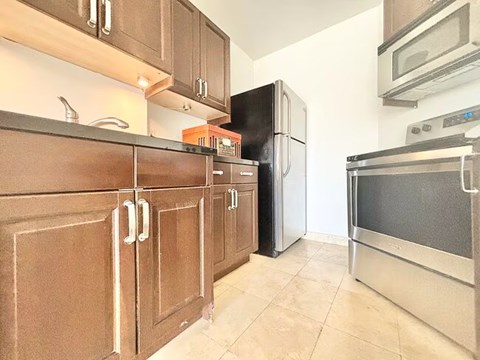 A kitchen with brown cabinets and a black refrigerator.