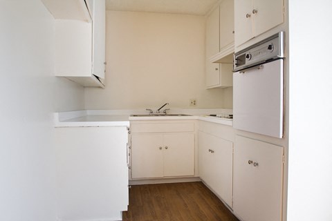 an empty kitchen with white cabinets and a stove and refrigerator