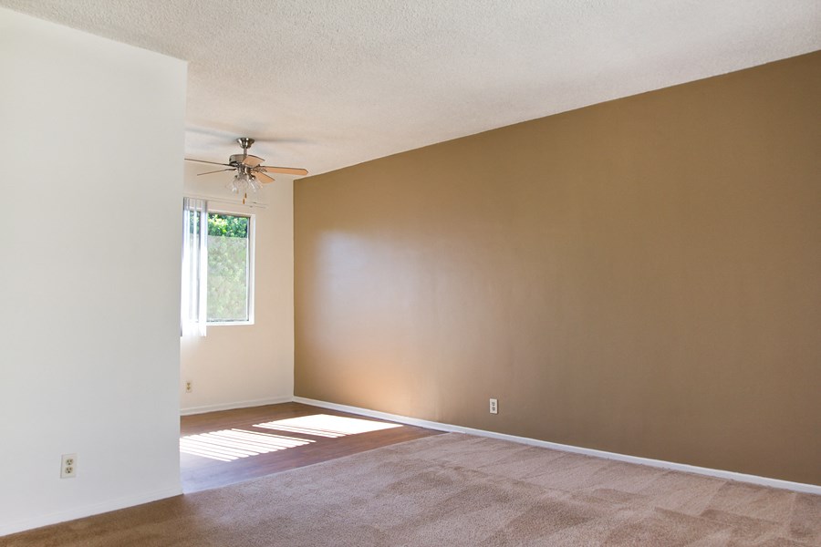 an empty living room with a ceiling fan and a window