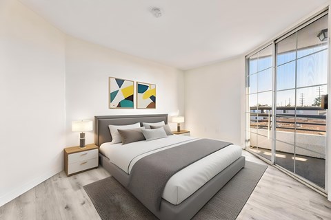 A bedroom with a large bed, a nightstand with a lamp, and a painting on the wall.
