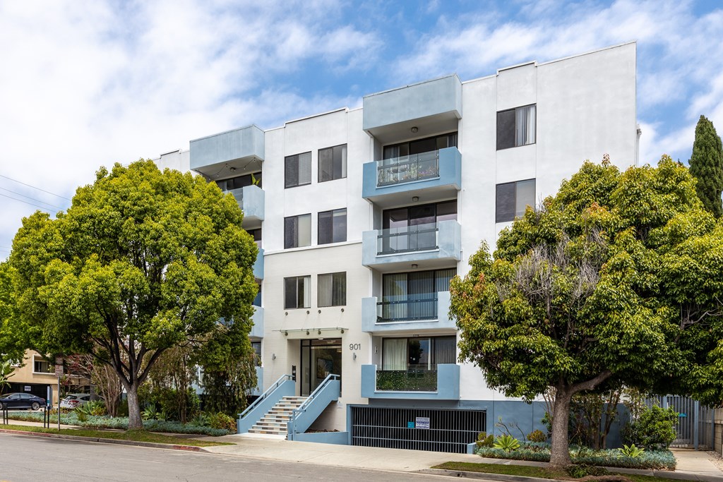 a white apartment building with blue stairs and trees