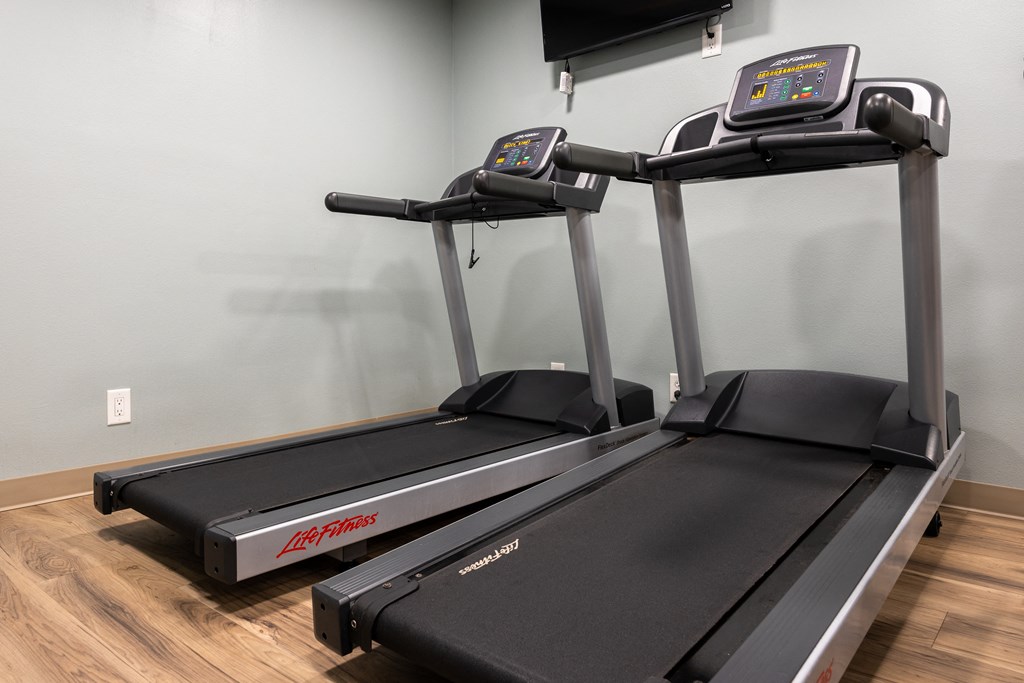 two treadmills in an indoor gym with a tv