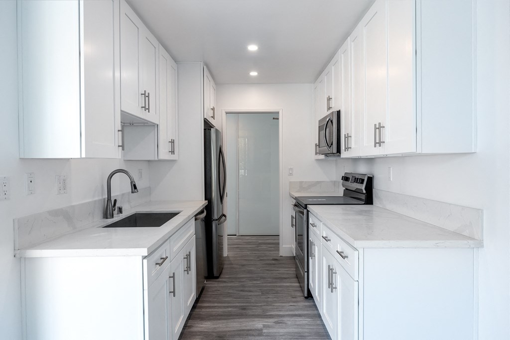 a kitchen with white cabinets and white counter tops and a white refrigerator and sink