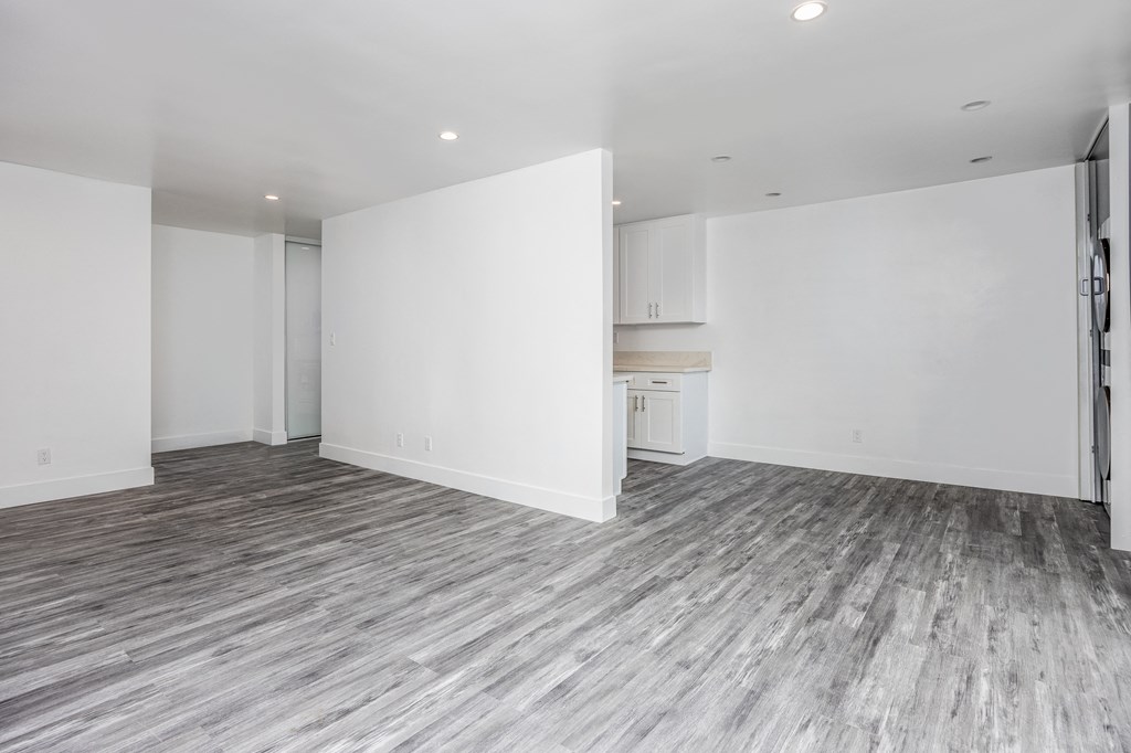 the living room and kitchen of a new home with white walls and flooring