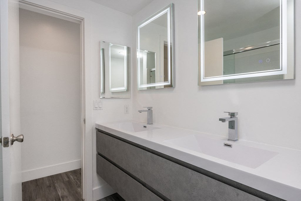 a bathroom with a sink and three mirrors on the wall