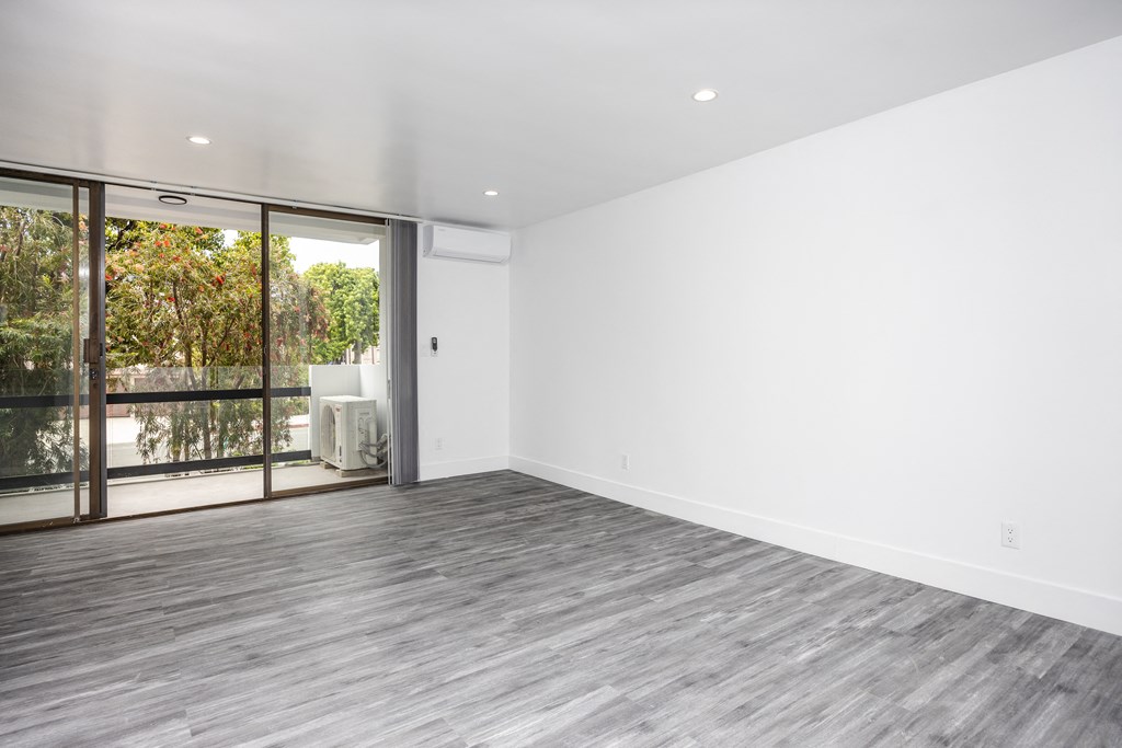 an empty living room with white walls and a sliding glass door