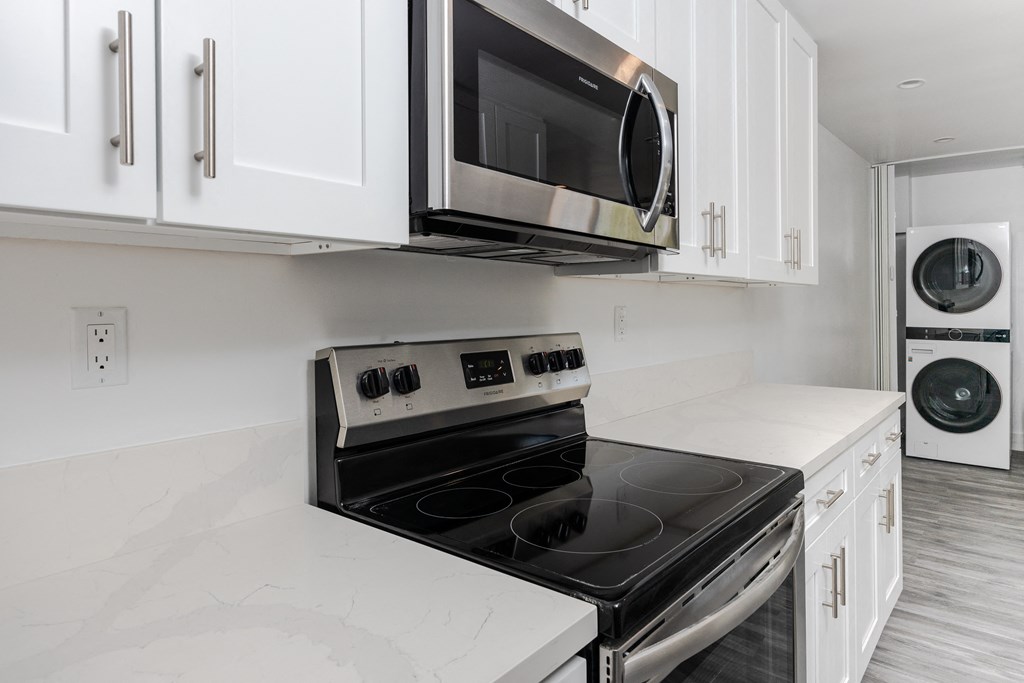 a kitchen with white cabinets and a stove and microwave