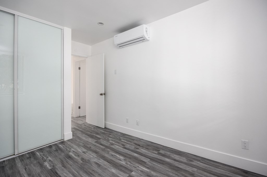 an empty room with white walls and a sliding glass door