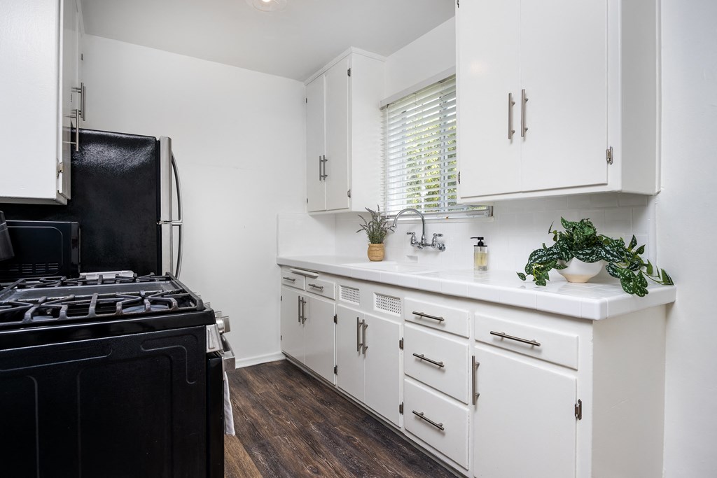 a kitchen with white cabinets and a black stove