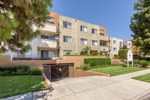 an apartment building with a gated entrance and a sidewalk