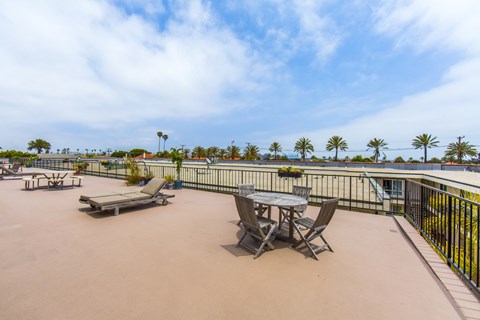A patio with a table and chairs overlooking palm trees.