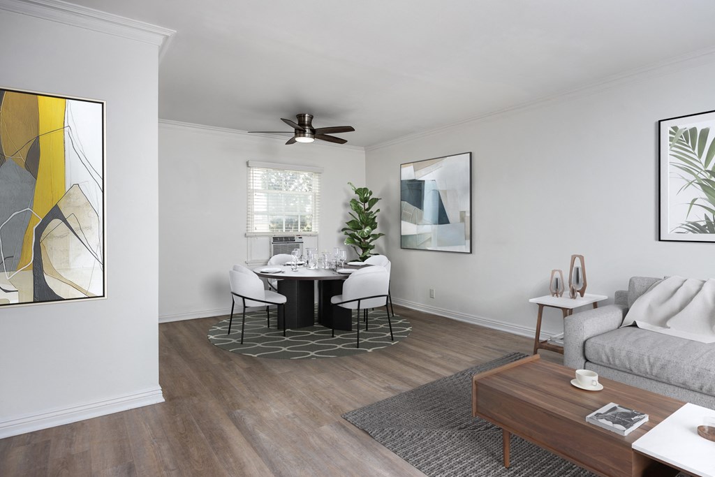 a living and dining room with white walls and a wood floor