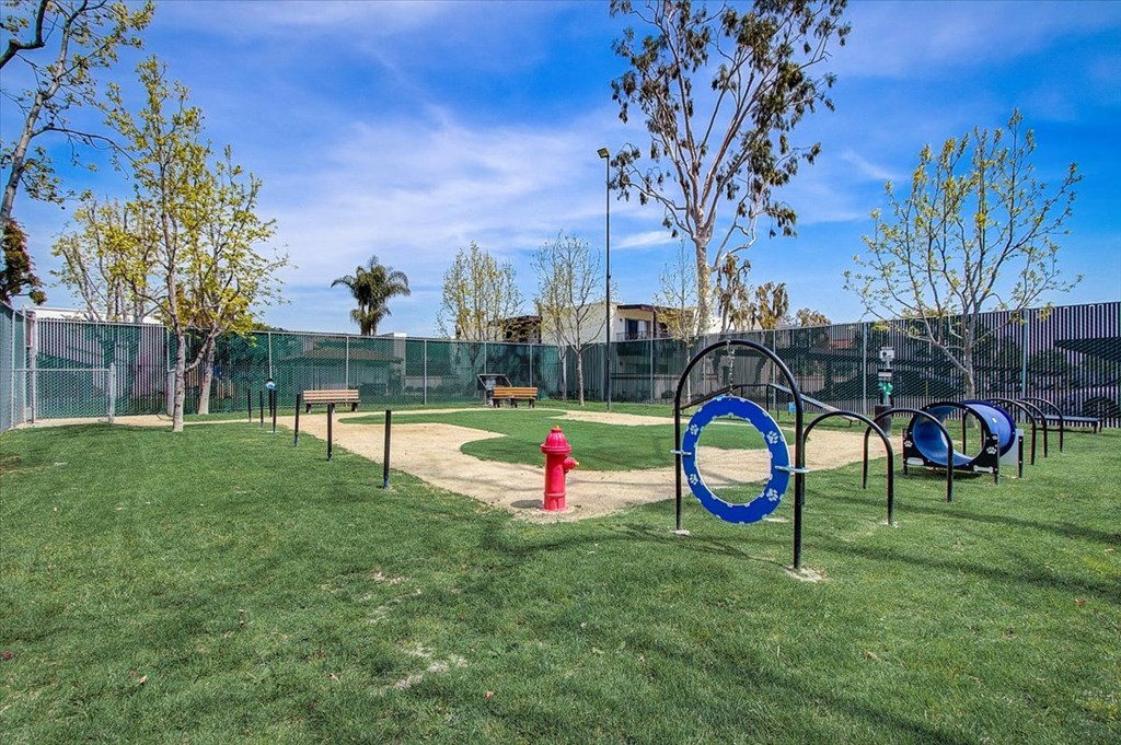 a fire hydrant in the middle of a grassy area with a chain link fence in