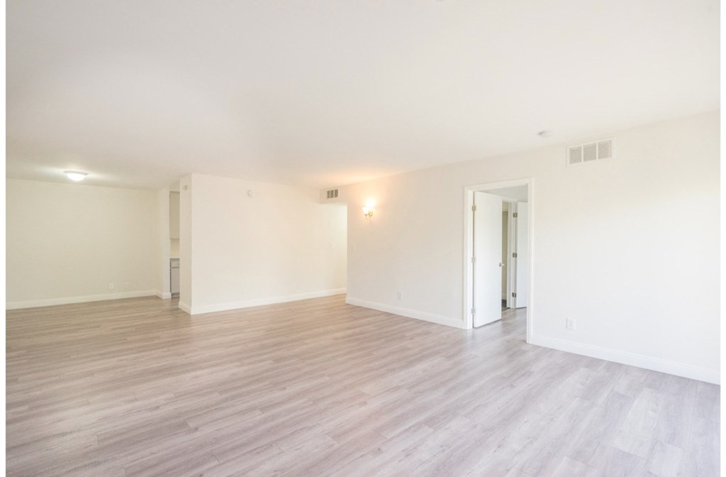 an empty living room with white walls and wood flooring