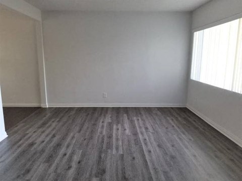 an empty living room with wooden floors and a window