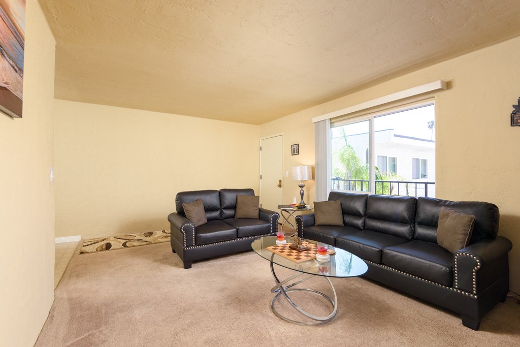 a living room with leather couches and a glass coffee table