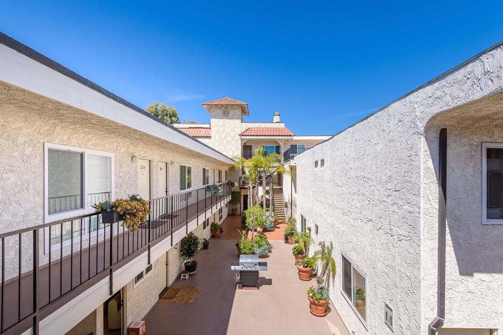 a courtyard between two buildings with benches and potted plants