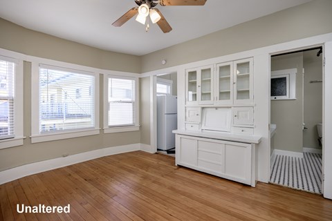 A kitchen with white cabinets and a wooden floor.
