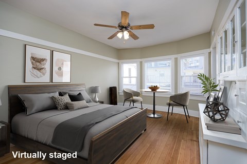 A bedroom with a bed, chair, and a ceiling fan.