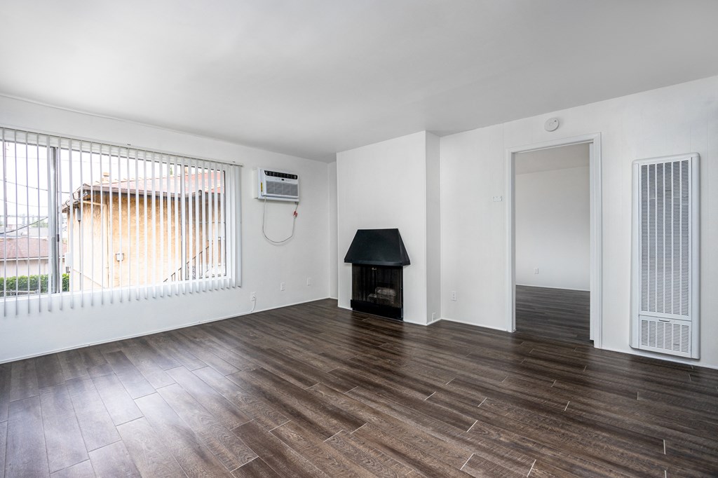 an empty living room with wood floors and a fireplace