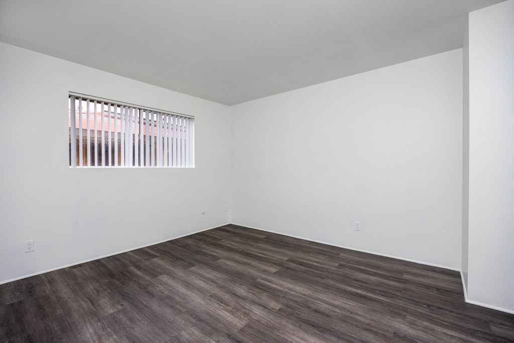 an empty room with white walls and wooden floors and a window