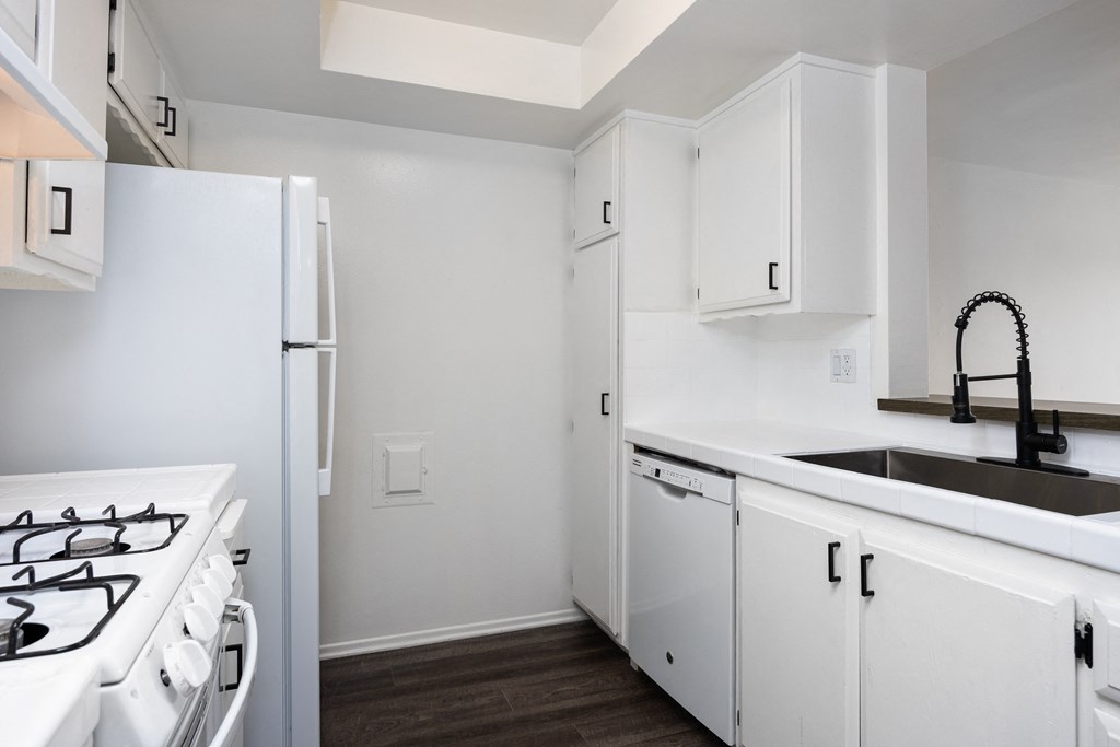 an empty kitchen with white cabinets and a white stove and refrigerator