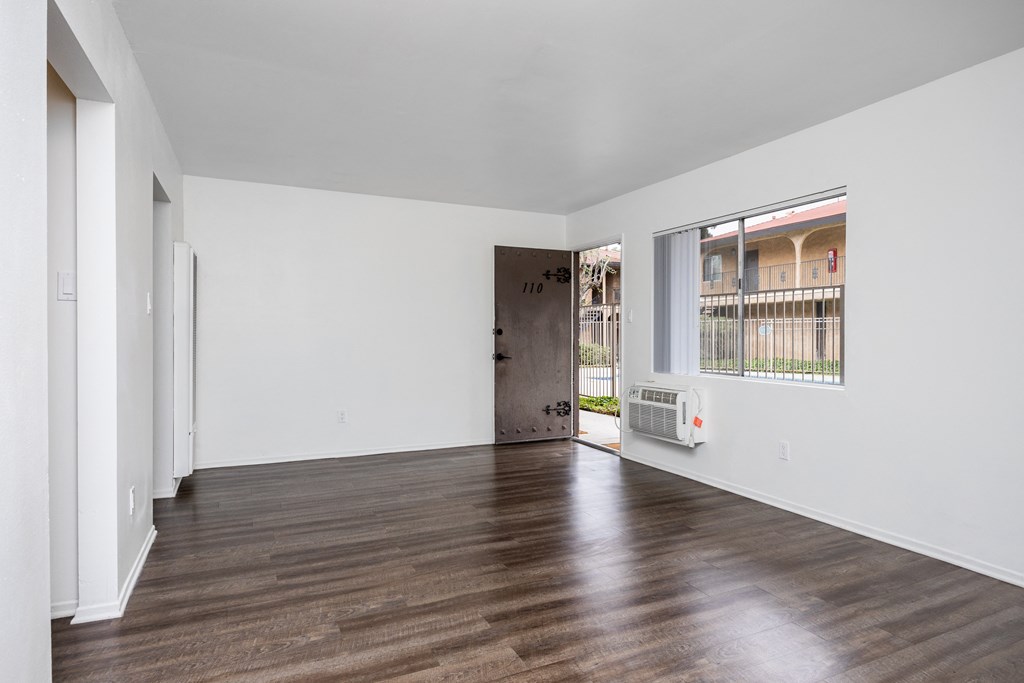 a living room with white walls and a large window and wooden floors