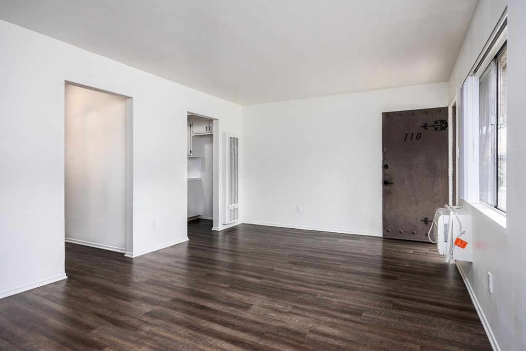 an empty living room with white walls and wood floors