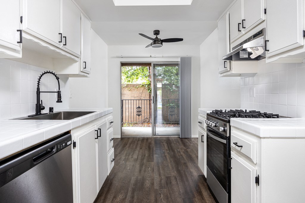 a kitchen with white cabinets and stainless steel appliances and a sliding glass door