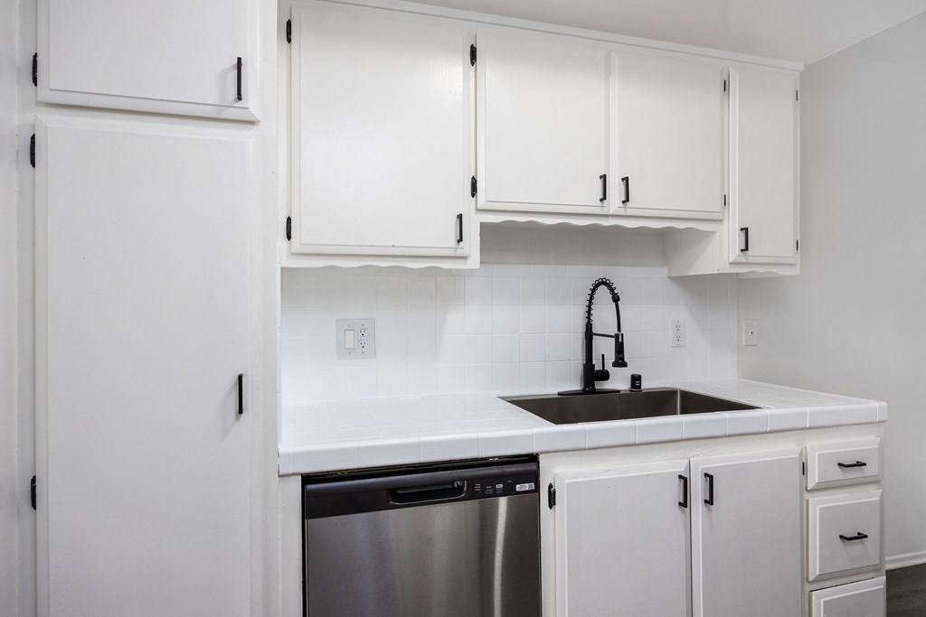 an empty kitchen with white cabinets and a sink