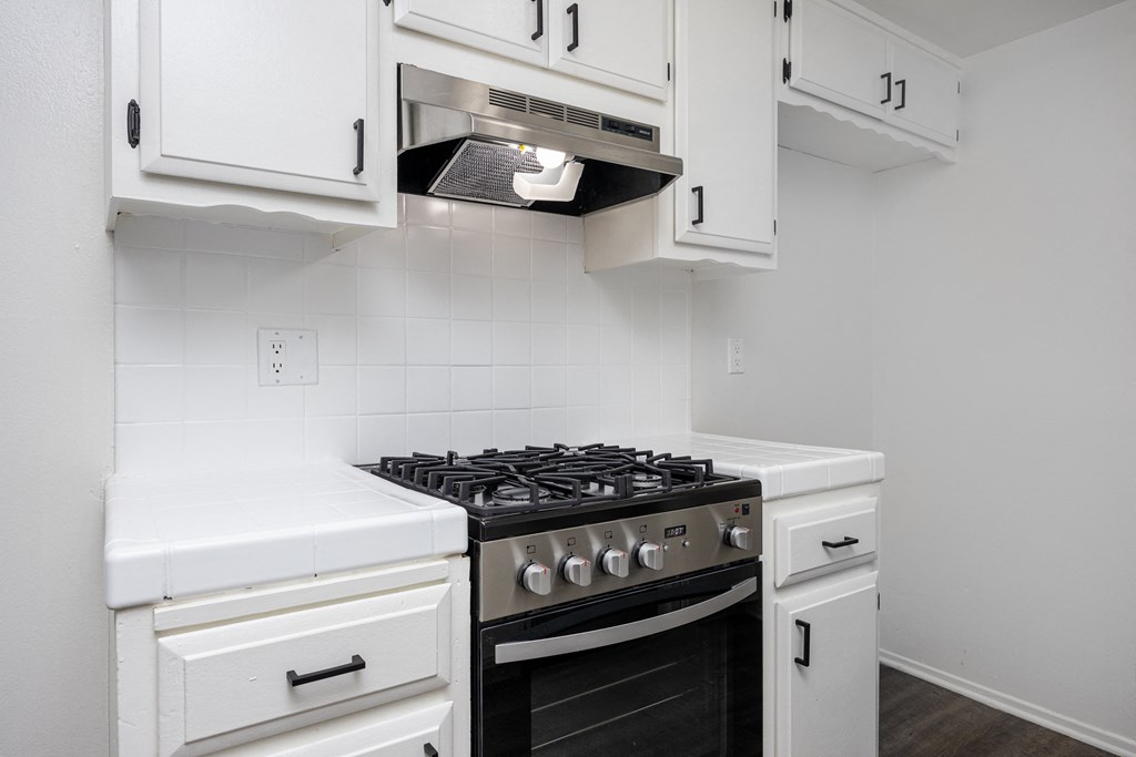 an empty kitchen with white cabinets and a stove and microwave
