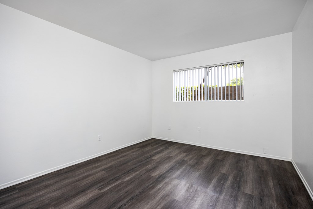 an empty room with white walls and wood floors and a window