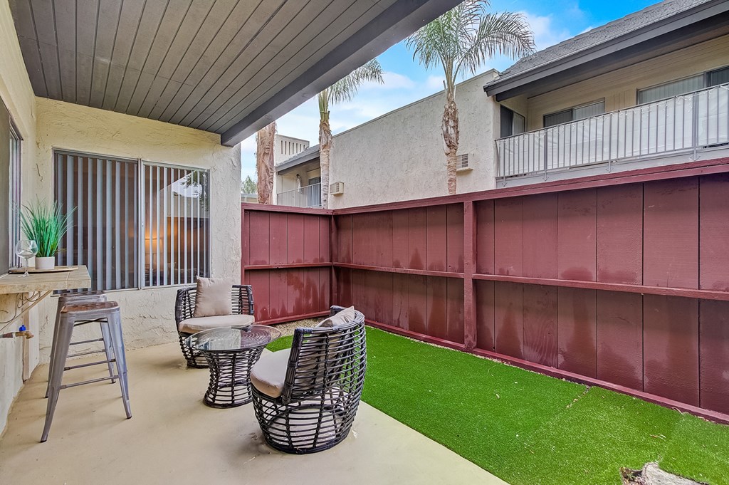 a patio with a table and chairs and a grassy area