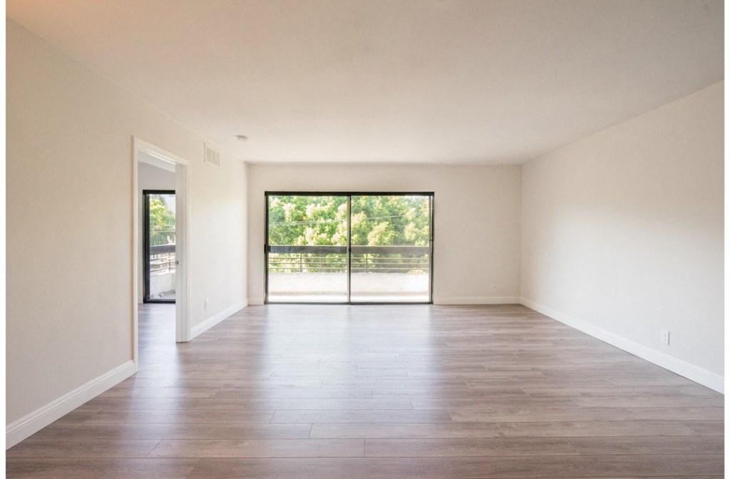 an empty living room with wood floors and sliding glass doors