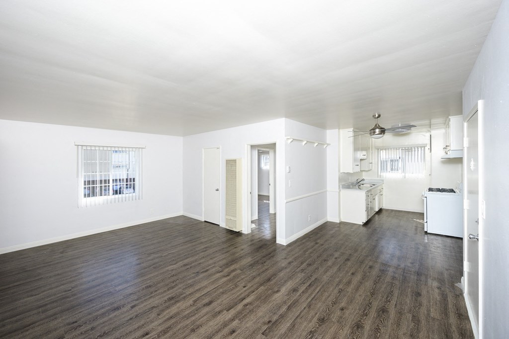 an empty living room and kitchen with white walls and wood floors