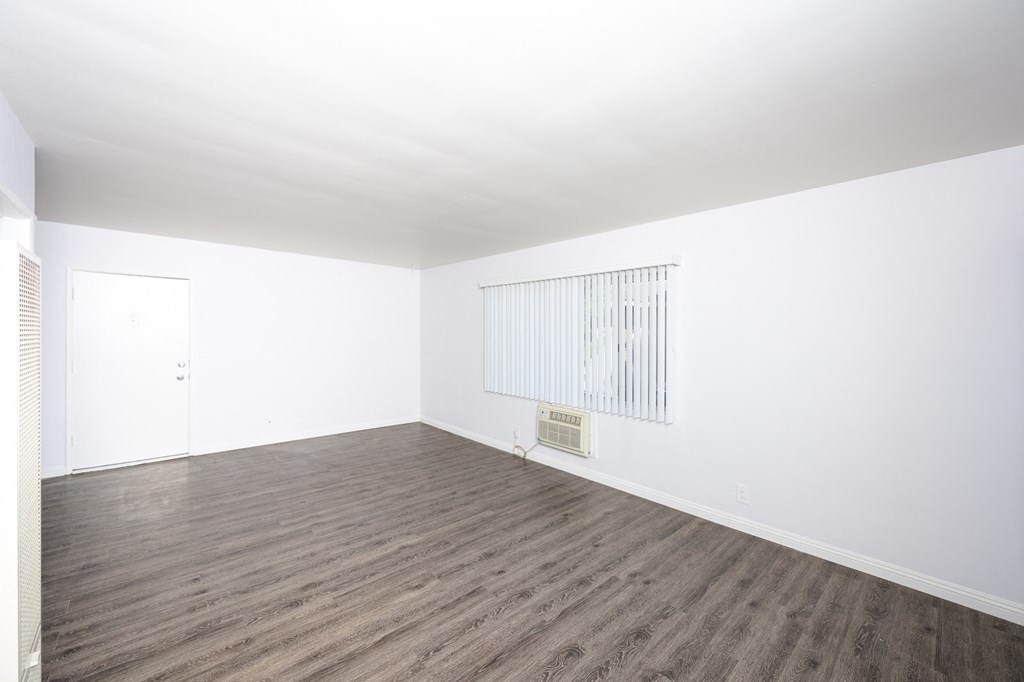 an empty room with white walls and wood floors