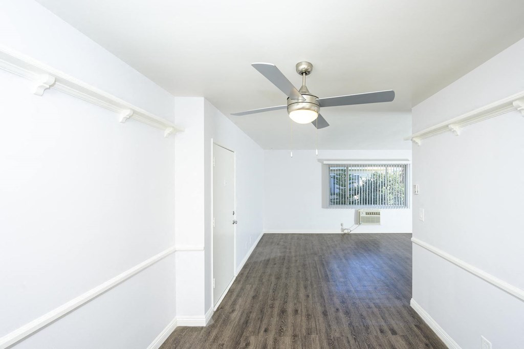 a living room with white walls and a ceiling fan